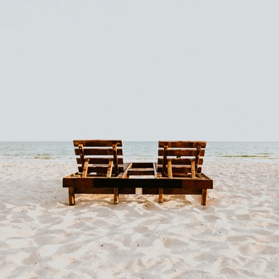 白天白色沙滩上的棕色木椅